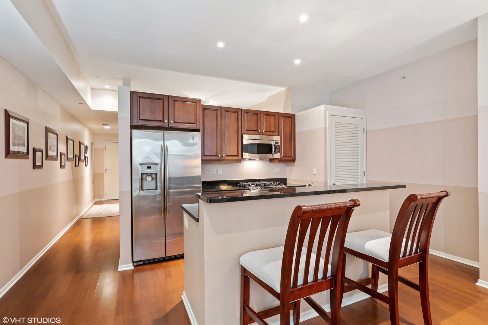 310 South Michigan Avenue, Unit 1010 Chicago, IL 60604 - Photo 7 of 15 a kitchen with stainless steel appliances granite countertop a refrigerator a stove top oven and a dining table with wooden floor