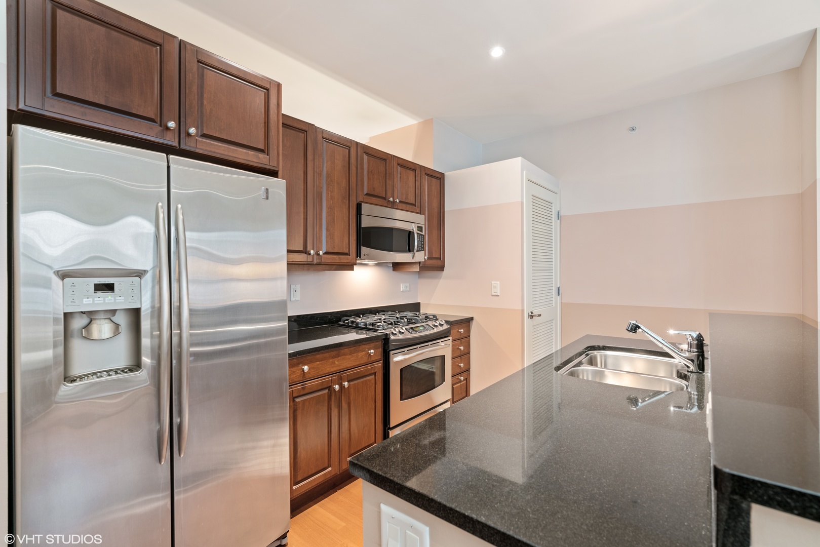 310 South Michigan Avenue, Unit 1010 Chicago, IL 60604 - Photo 8 of 15 a kitchen with stainless steel appliances granite countertop a refrigerator a stove and a sink with wooden floor