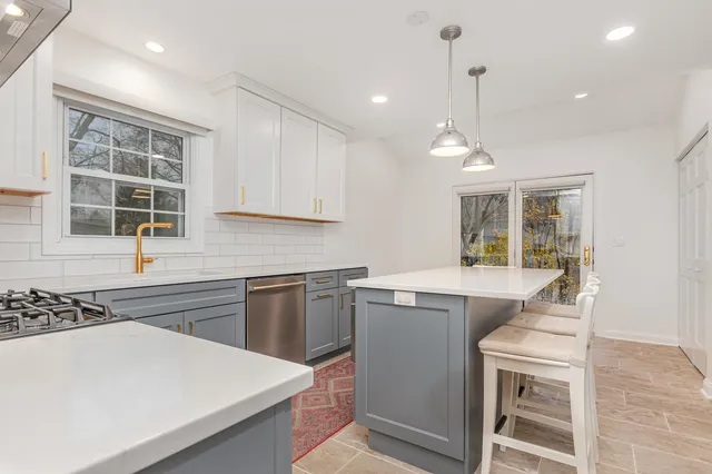 a kitchen that has a sink a stove and chairs