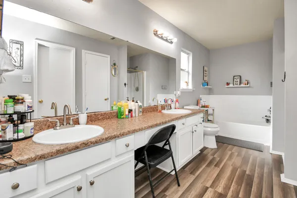 a bathroom with a granite countertop double vanity sink a mirror and a bathtub