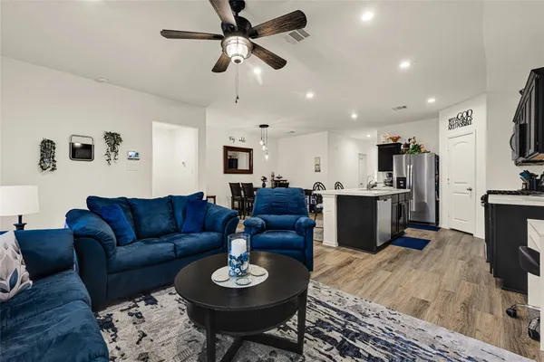 a living room with furniture kitchen view and a wooden floor