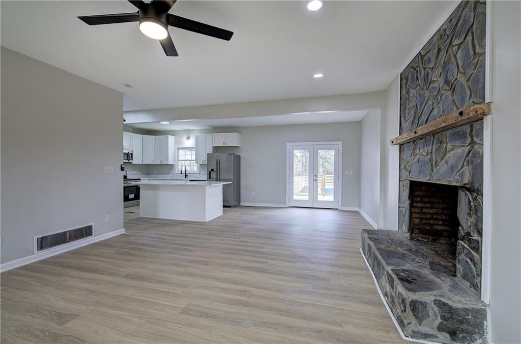 2193 West Ellis Road Griffin, GA 30223 - Photo 5 of 26 a view of a kitchen and an empty room with wooden floor and a fireplace