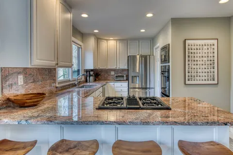 a kitchen with kitchen island granite countertop wooden cabinets and a sink