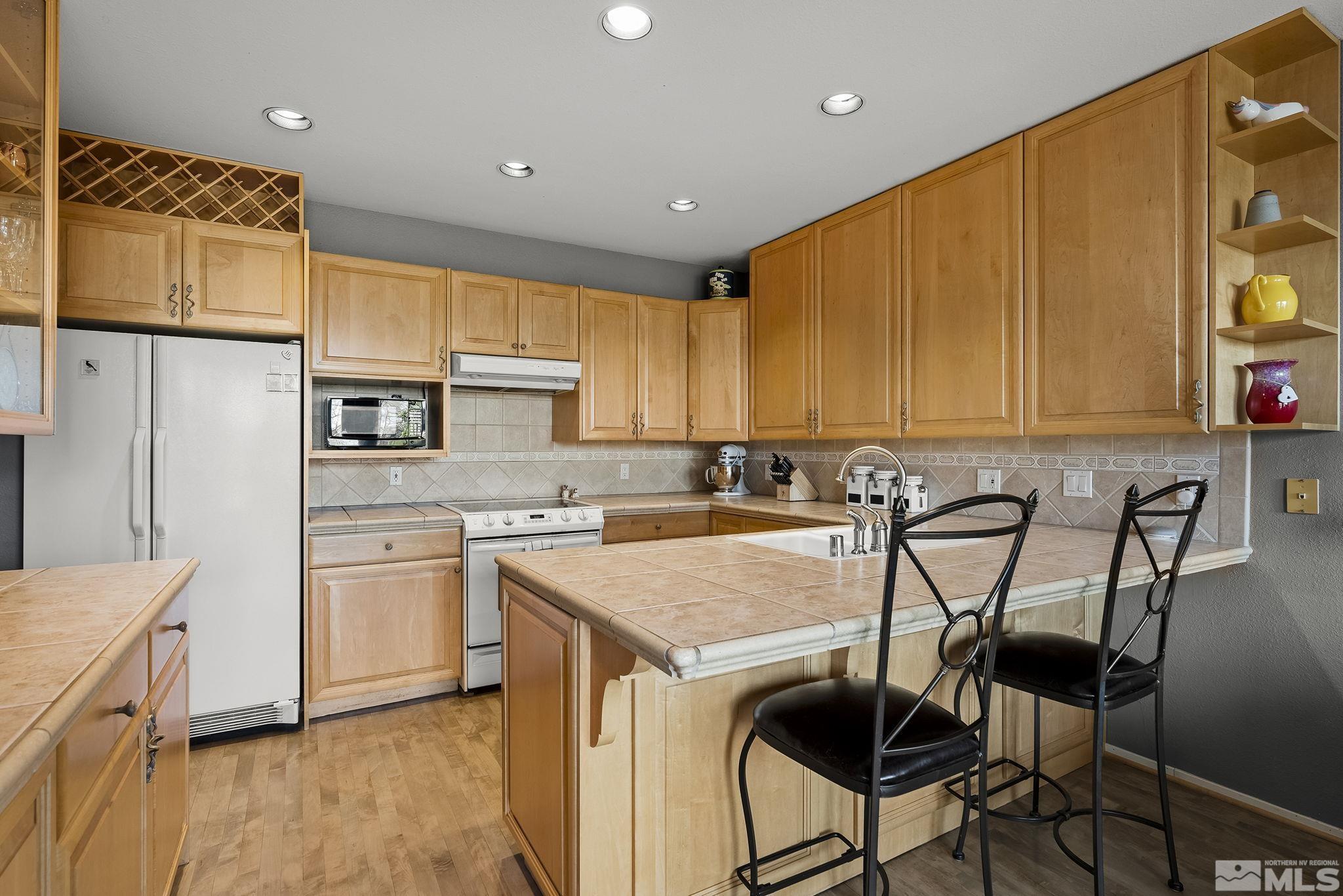 2390 High Terrace Drive Reno, NV 89509 - Photo 11 of 36 a kitchen with stainless steel appliances granite countertop a table chairs sink refrigerator and cabinets