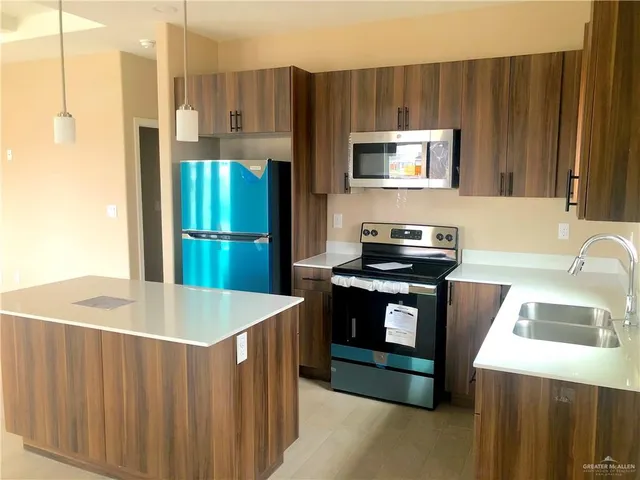 a kitchen with kitchen island a stove a sink and a refrigerator