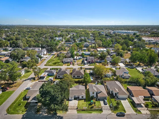 an aerial view of residential houses with outdoor space and trees