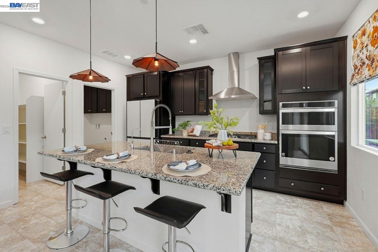 1444 Meridian Street Manteca, CA 95337 - Photo 12 of 45 a kitchen with stainless steel appliances kitchen island granite countertop a stove a sink a dining table and chairs with wooden floor