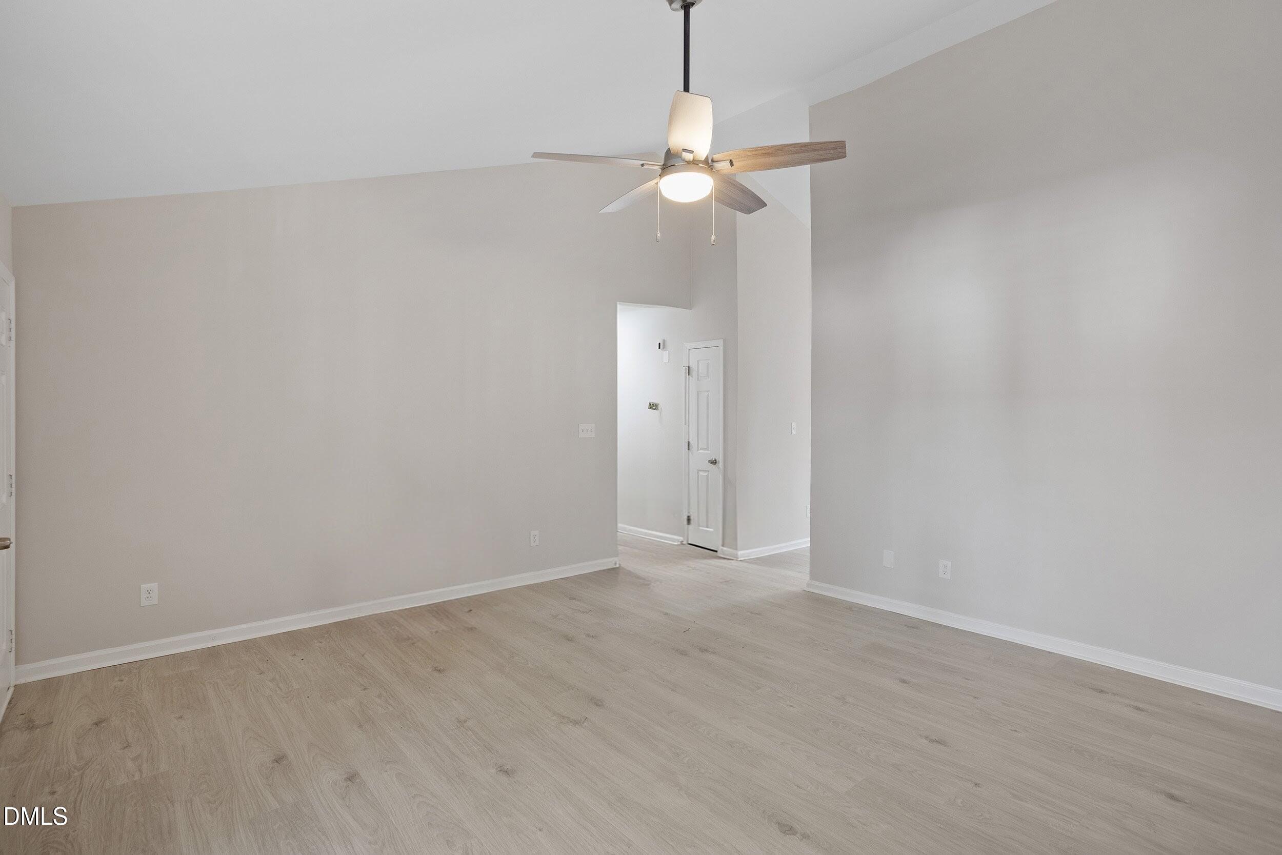 247 Tillamook Drive Wake Forest, NC 27587 - Photo 13 of 30 an empty room with a chandelier fan and wooden floor