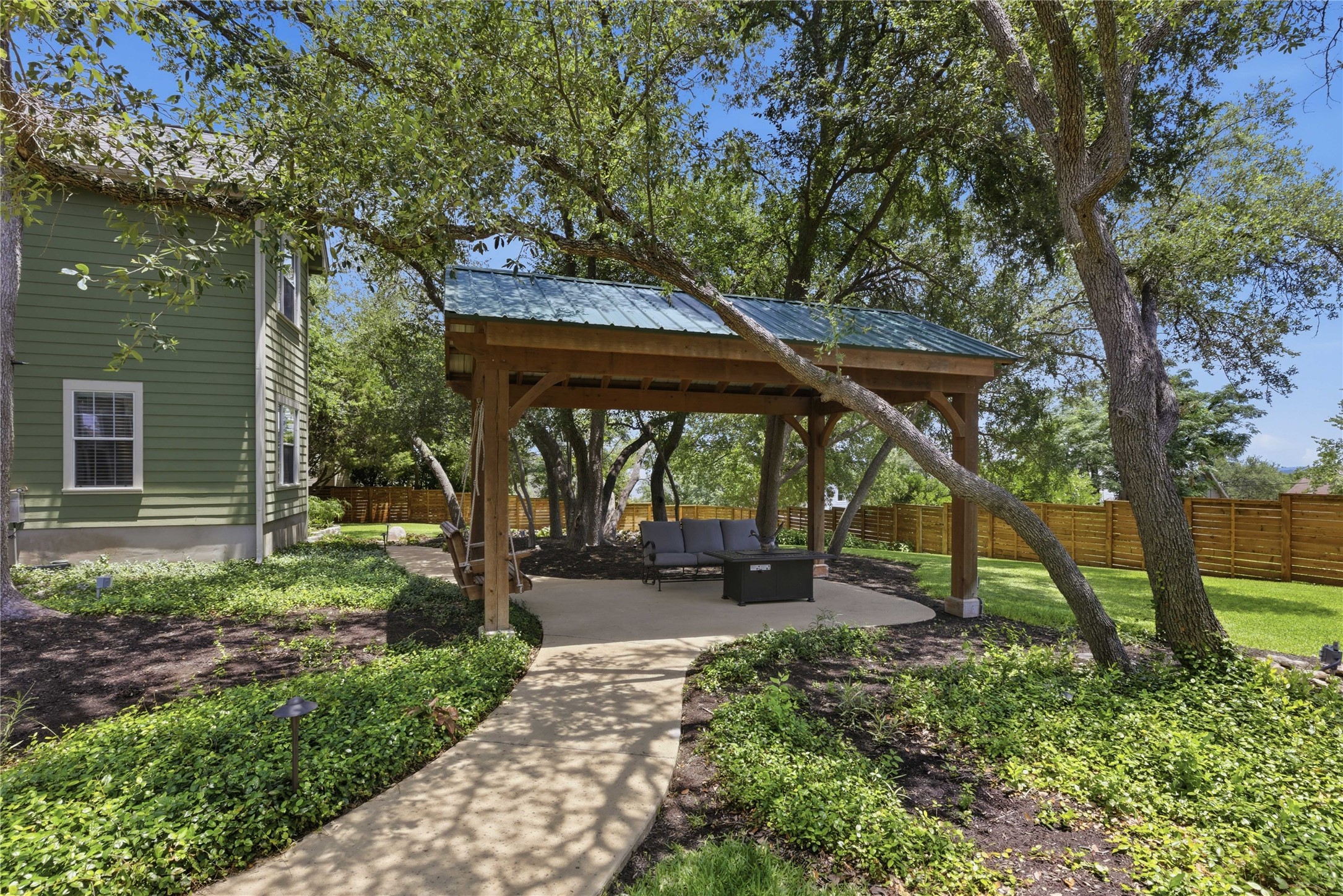 1204 Orlando Road Austin, TX 78733 - Photo 23 of 40 Lush landscaping and mature trees frame this delightful covered patio, perfect for outdoor enjoyment.