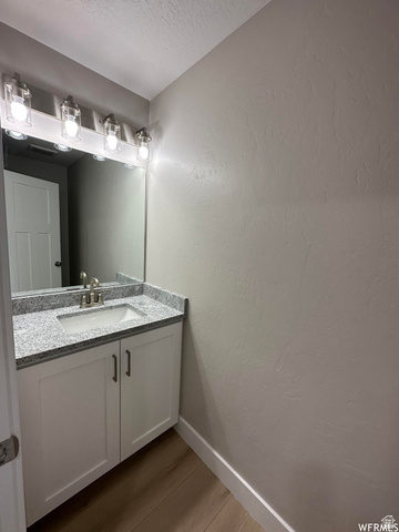 1171 West 2330 North Helper, UT 84526 - Photo 22 of 26 Bathroom featuring vanity, a textured wall, wood finished floors, and a textured ceiling