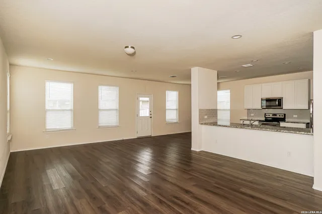 a view of empty room with wooden floor and a window
