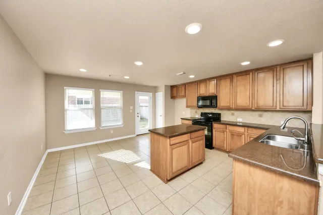 a kitchen with stainless steel appliances granite countertop a sink and a stove top oven with wooden floor