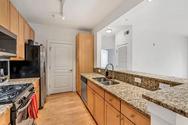 a kitchen with stainless steel appliances granite countertop a sink stove and refrigerator
