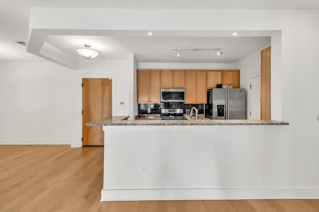 a view of kitchen with stainless steel appliances granite countertop window and sink