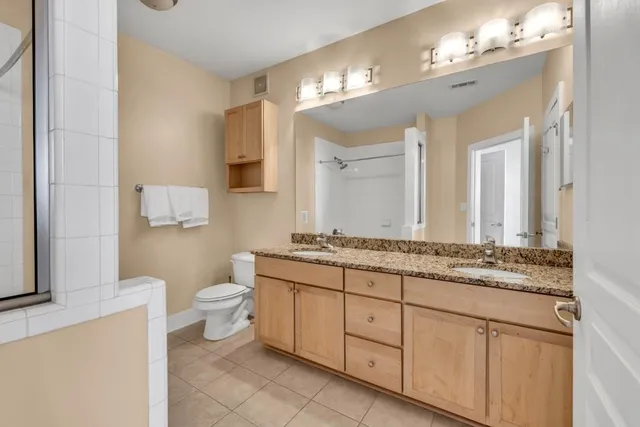 a bathroom with a granite countertop toilet a sink and a mirror