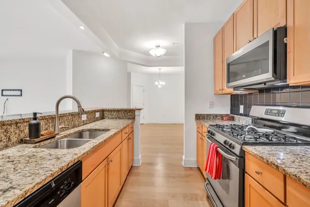 a kitchen with stainless steel appliances granite countertop a sink a stove and a wooden cabinets