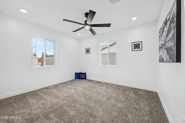 an empty room with windows and ceiling fan