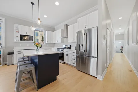 a kitchen with stainless steel appliances granite countertop a refrigerator a sink a stove a oven a kitchen island with a dining table and chairs