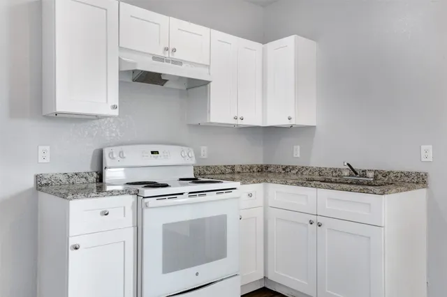 a kitchen with granite countertop white cabinets and white appliances
