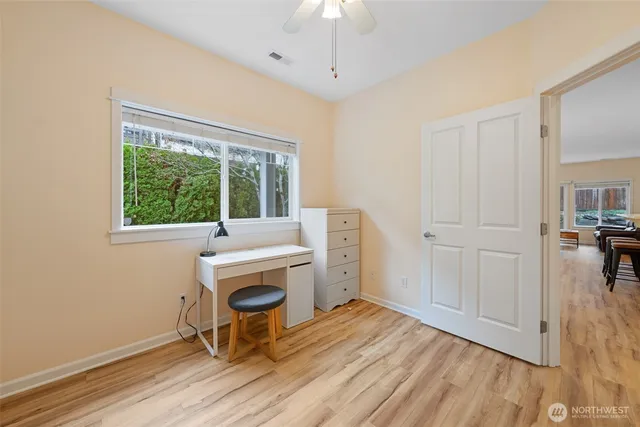 a view of a workspace with wooden floor and windows