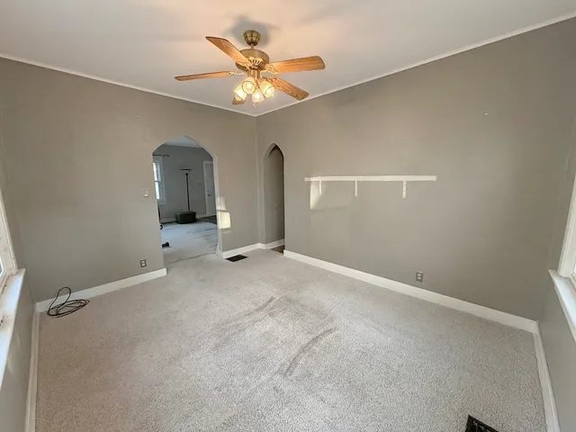 an empty room with a chandelier fan and a large window