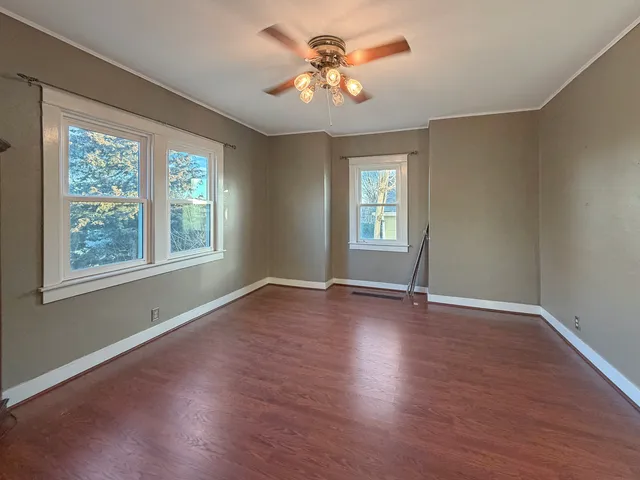 a view of an empty room with window and wooden floor