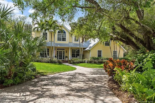 a front view of a house with a yard and potted plants