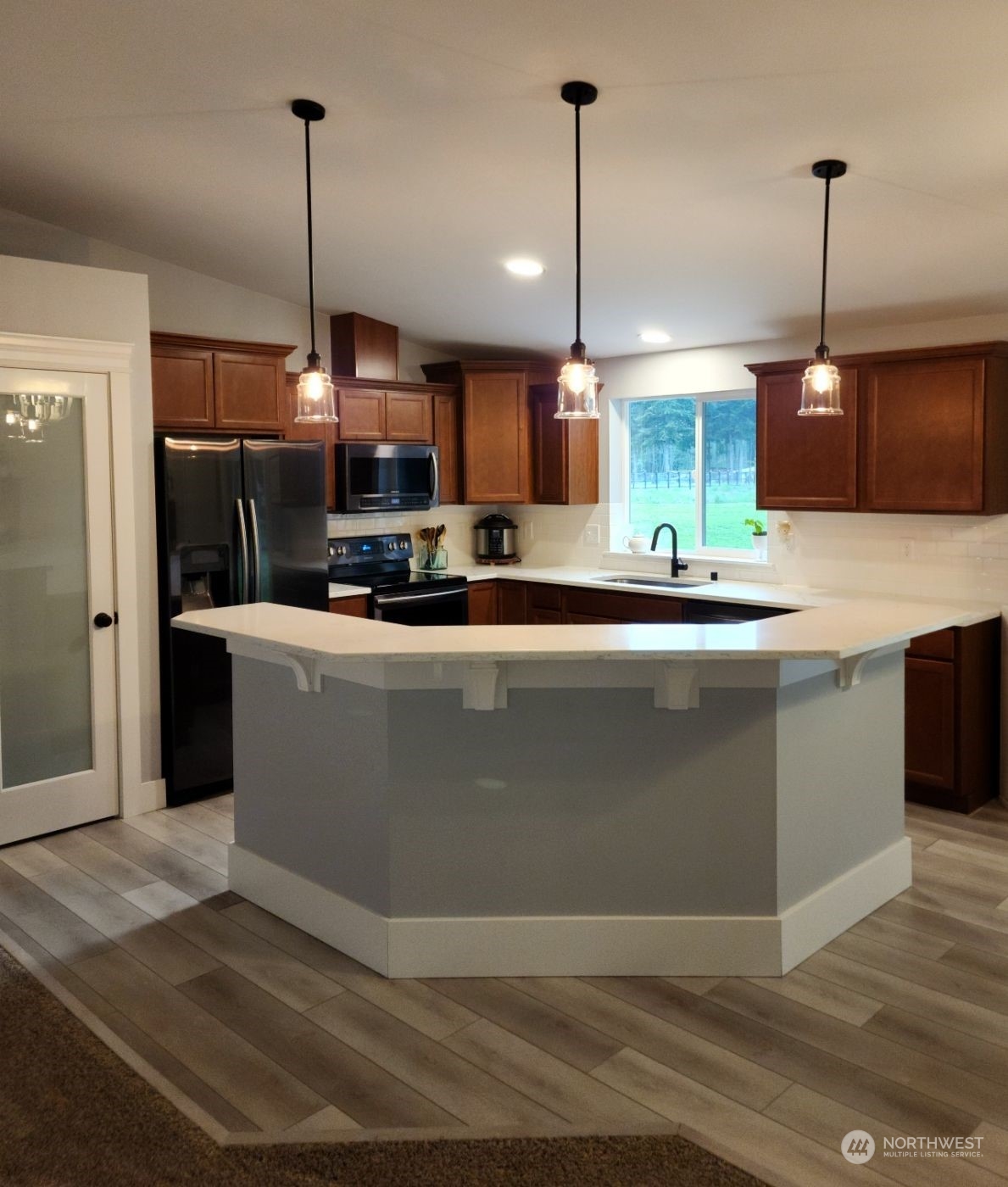 19312 Patterson Road East Orting, WA 98360 - Photo 13 of 39 a kitchen with kitchen island stainless steel appliances a sink a counter top cabinets and a wooden floor
