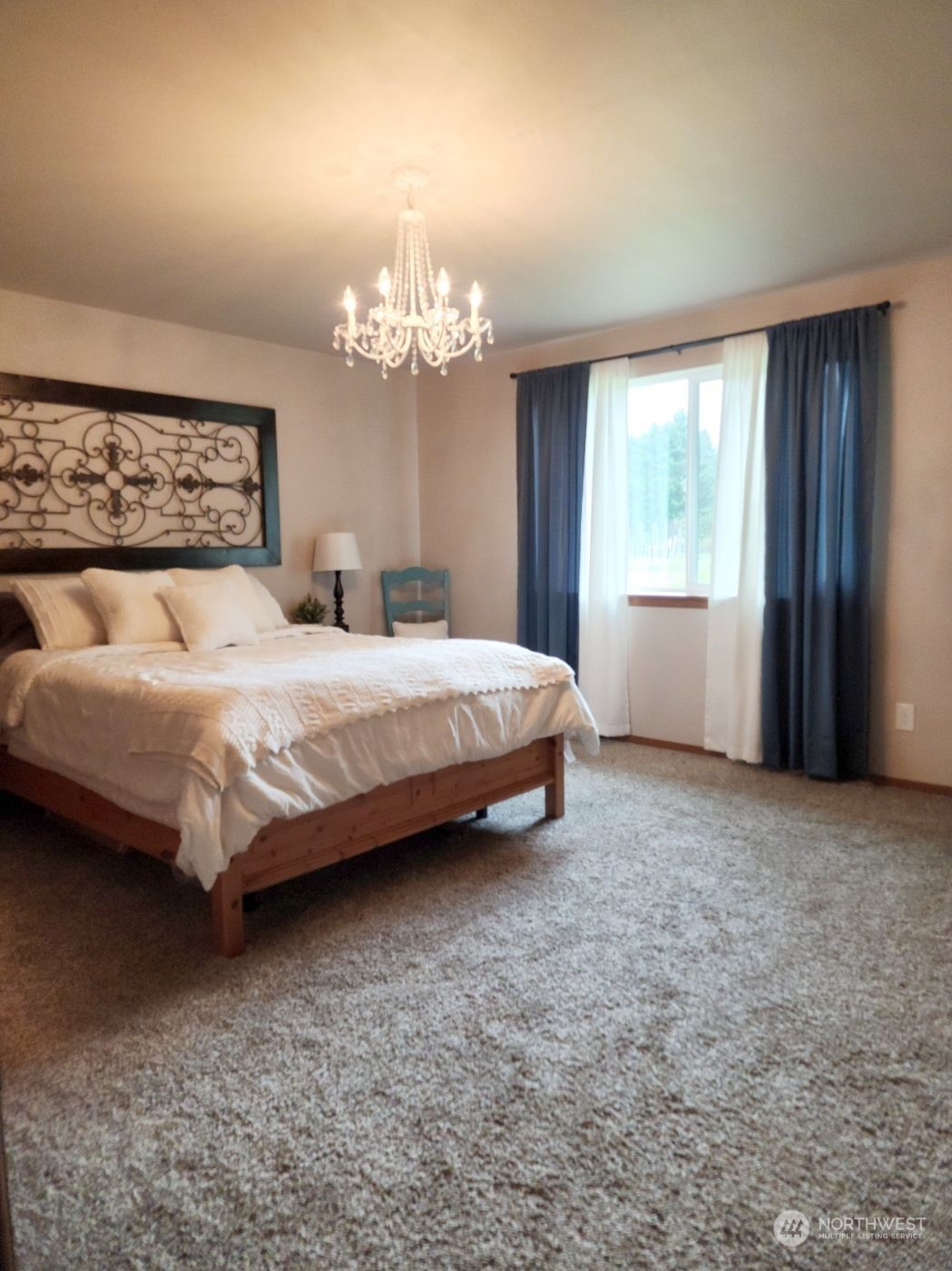 19312 Patterson Road East Orting, WA 98360 - Photo 20 of 39 a spacious bedroom with a bed chandelier and a window