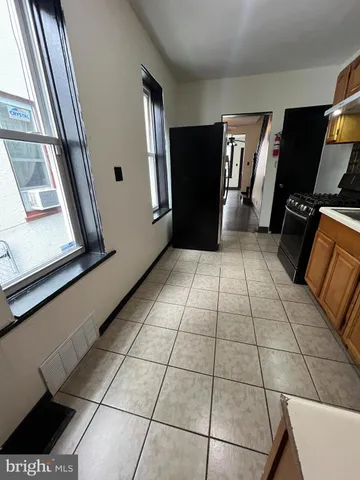 a view of a refrigerator in kitchen and an empty room