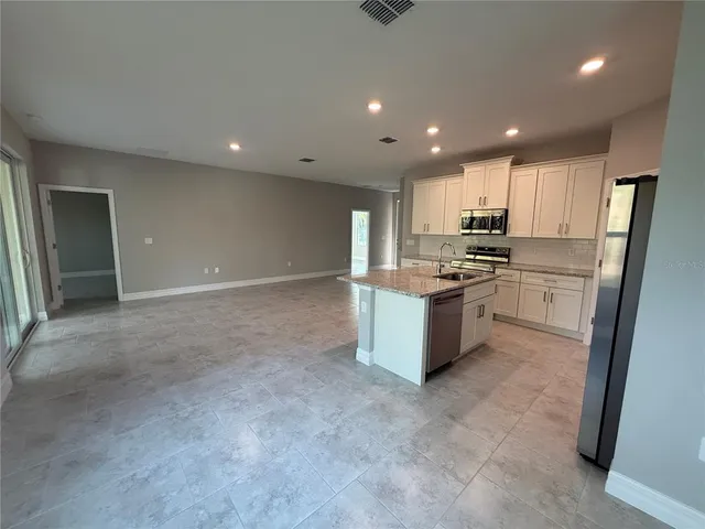 a large kitchen with stainless steel appliances lots of counter top space cabinets and a refrigerator