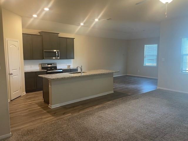 205 Lake Ridge Princeton, TX 75407 - Photo 13 of 13 Kitchen featuring stainless steel appliances, light stone countertops, dark colored carpet, a center island with sink, and open floor plan