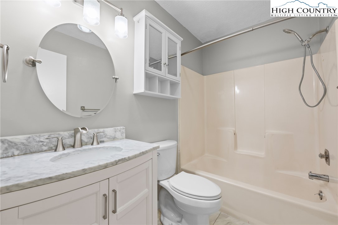 1469 West King Street, Unit 201 Boone, NC 28607 - Photo 17 of 19 a bathroom with a granite countertop sink a toilet and a bathtub
