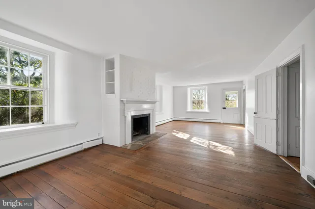 a view of empty room with wooden floor and fireplace