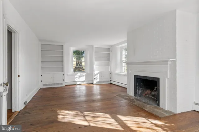 a view of empty room with wooden floor and fireplace