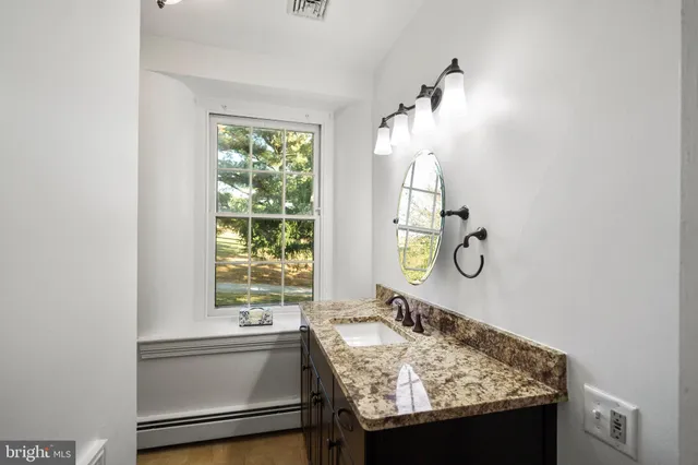 a bathroom with a granite countertop sink and a tub