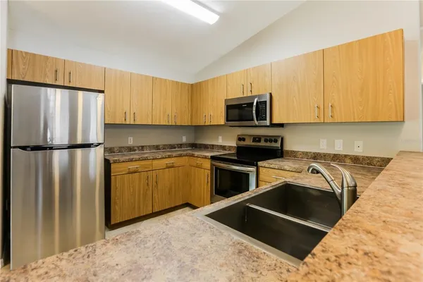 a kitchen with granite countertop a refrigerator sink and white cabinets