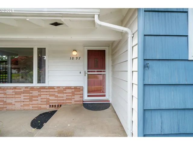 a view of an empty room with wooden floor fireplace and a window