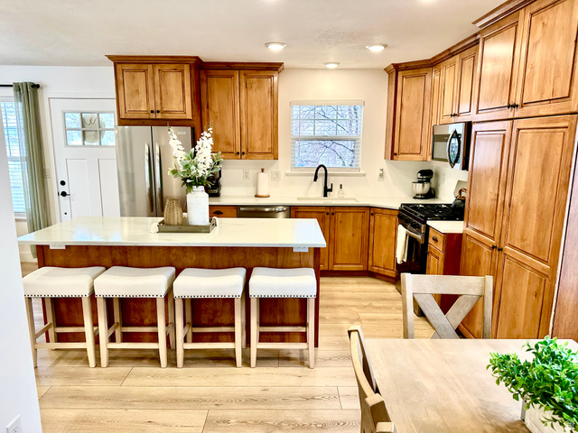 7818 North Windhover Road Eagle Mountain, UT 84005 - Photo 10 of 32 Kitchen featuring wood-finish cabinetry, stainless steel appliances, a center island with countertop seating, recessed lighting, and wood-finish flooring