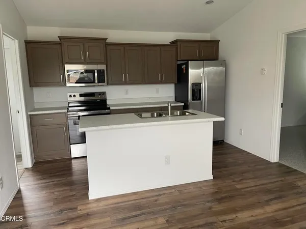 a utility room with stainless steel appliances wooden floor and view living room