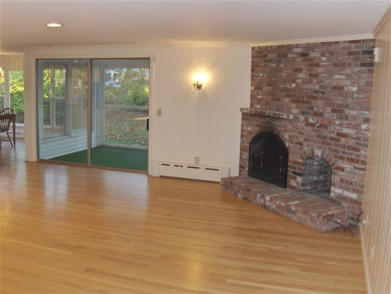 110 Round Cove Road Chatham, MA 02633 - Photo 2 of 16 an empty room with wooden floor and a fireplace