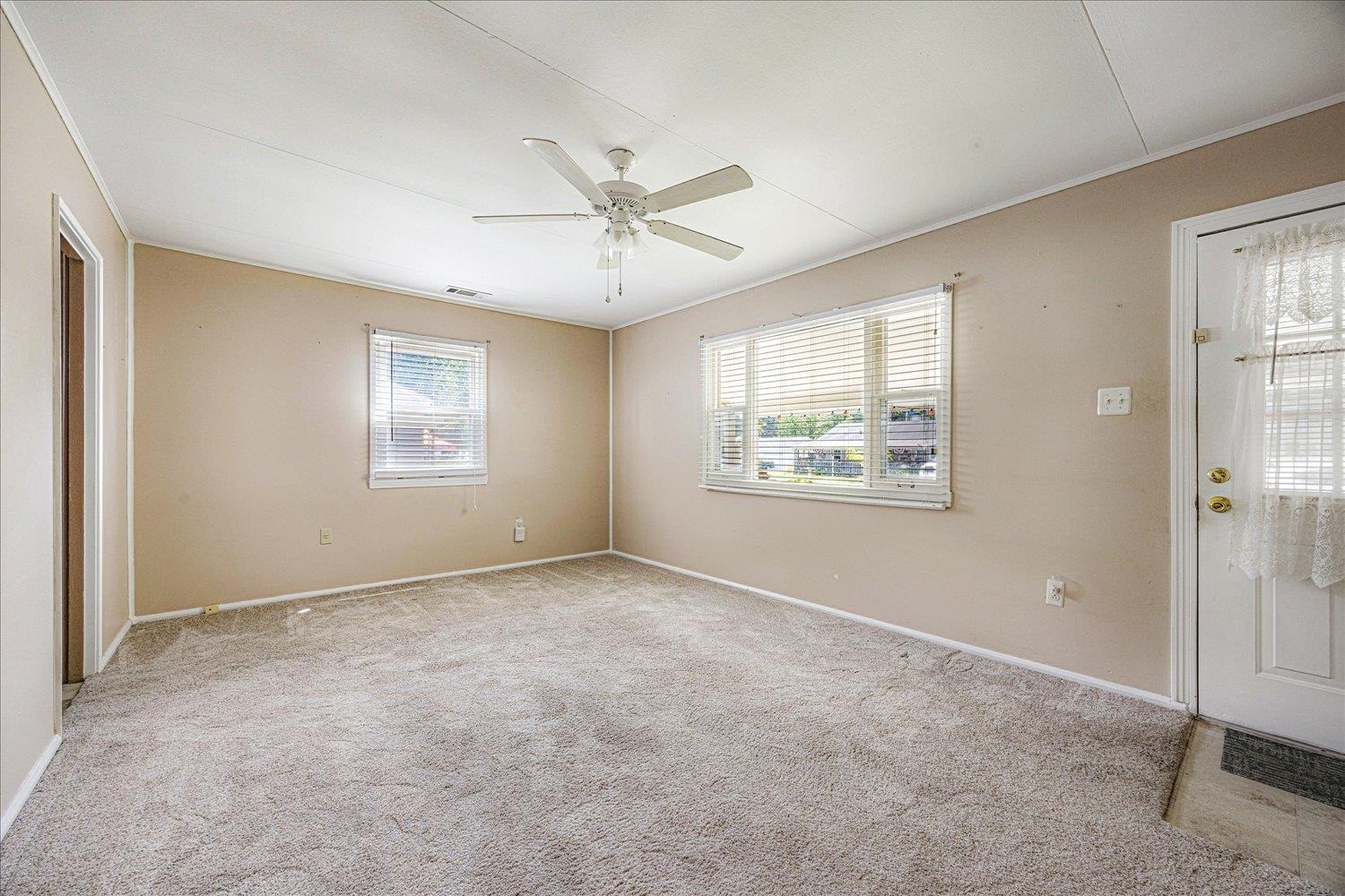 4690 Montgomery Road Millington, TN 38053 - Photo 9 of 26 Empty room featuring light carpet, healthy amount of natural light, a ceiling fan, and ornamental molding
