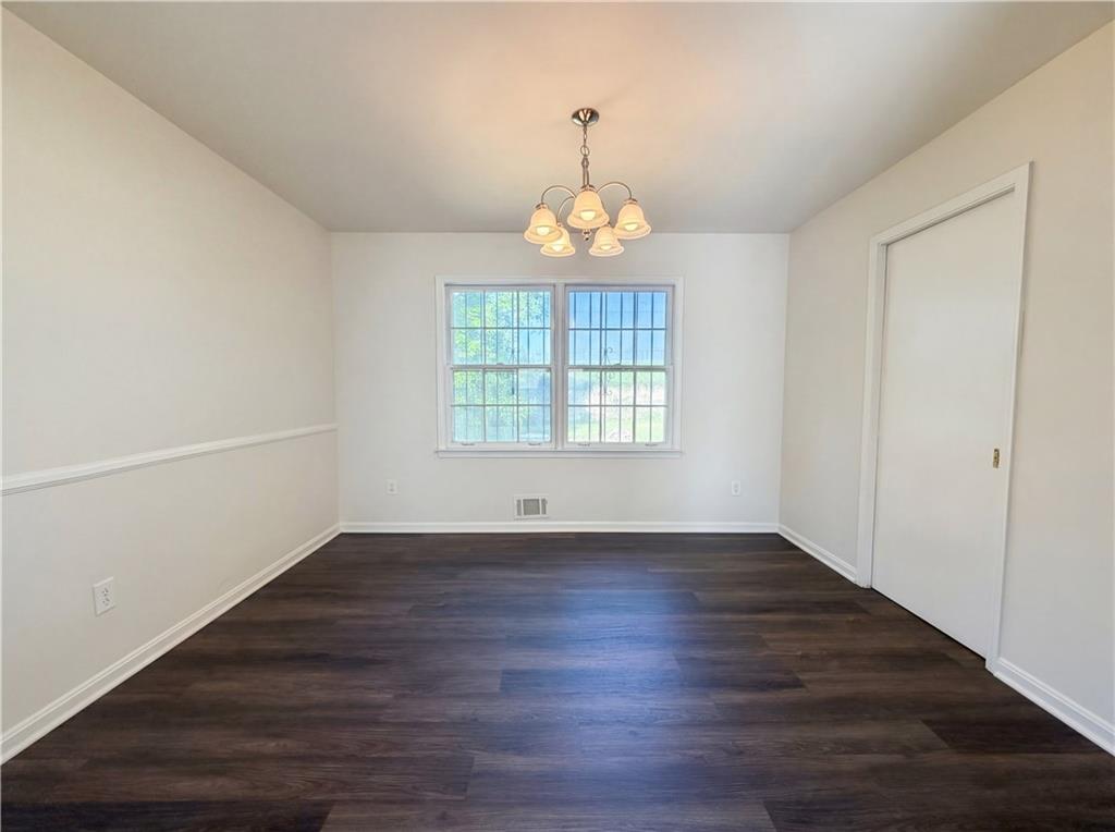 4055 Tecumseh Trail Conley, GA 30288 - Photo 12 of 30 an empty room with wooden floor chandelier and windows