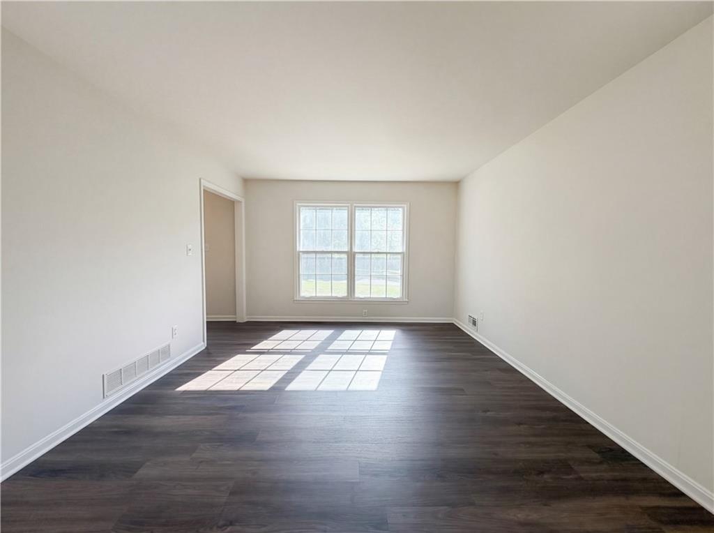 4055 Tecumseh Trail Conley, GA 30288 - Photo 6 of 30 an empty room with wooden floor and windows
