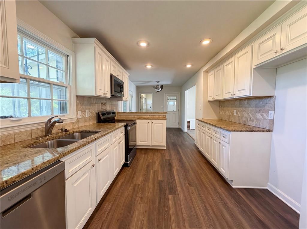 4055 Tecumseh Trail Conley, GA 30288 - Photo 7 of 30 a large kitchen with stainless steel appliances granite countertop a lot of counter space and wooden floors