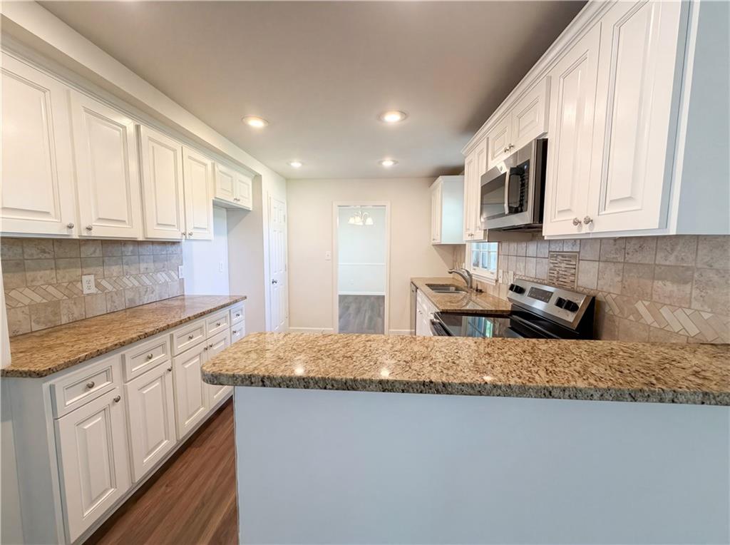 4055 Tecumseh Trail Conley, GA 30288 - Photo 9 of 30 a kitchen with kitchen island granite countertop a sink a stove a microwave and cabinets