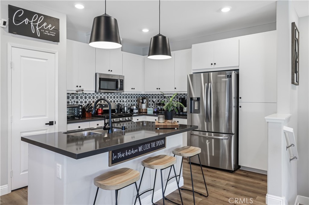 5604 Altamura Way, Unit 11 Fontana, CA 92336 - Photo 6 of 51 a kitchen with stainless steel appliances a refrigerator a sink a stove a dining table and chairs