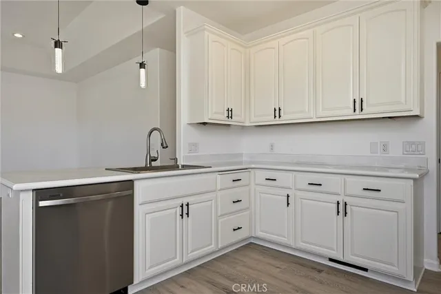 a kitchen with granite countertop a stove top oven a sink and white cabinets with wooden floor