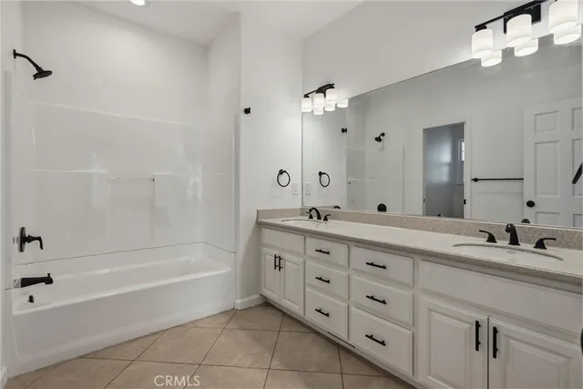 a bathroom with a tub sink double vanity and granite