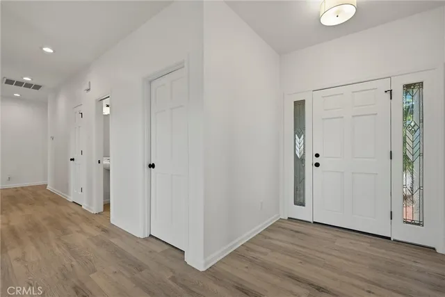 a view of an empty room with wooden floor and closet area